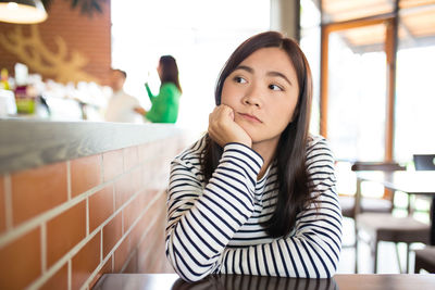 Thoughtful young woman sitting at restaurant