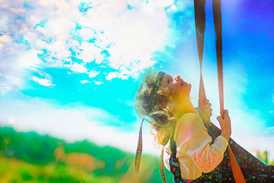 Low angle view of young woman against blue sky