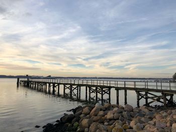 Pier over sea against sky during sunset