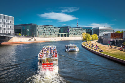 Boats in river against buildings in city