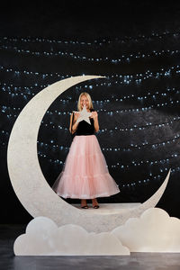 Portrait of young woman with arms raised against sky