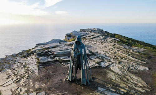 Monument to king arthur on a rock against the backdrop of the ocean
