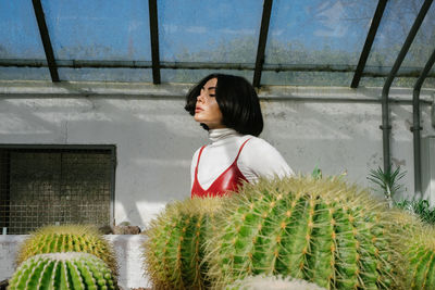 Young woman standing by plants against sky