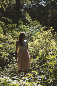 Woman standing amidst plants against trees