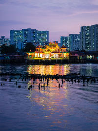 River and illuminated buildings in city at dusk