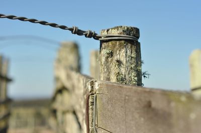 Close-up of old wooden post against sky