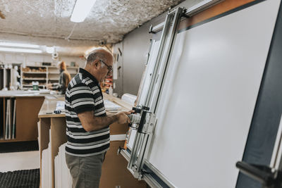 Side view of craftsman using screen printing while working in workshop