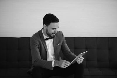 Young man using digital tablet while sitting on sofa at home