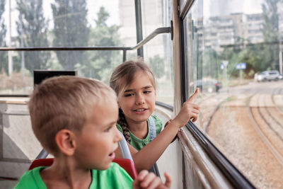 Kids ride in empty tram and look at the window with interest, public transportation, city tramway