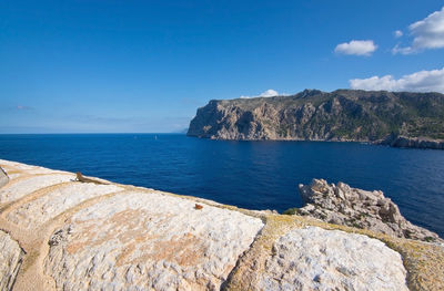 Scenic view of sea by cliff against blue sky