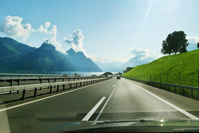 Road leading towards mountains seen through car windshield