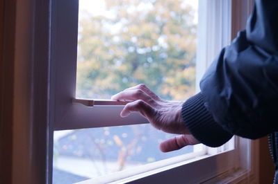 Midsection of man holding glass window