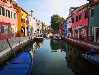 Boats moored in canal amidst buildings in city