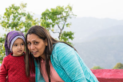 Portrait of mother with daughter against mountain