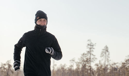 Full length of a happy middle-aged athlete running in nature on a snowy winter day. outdoor fitness