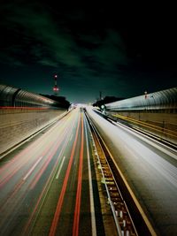 Light trails on road against sky at night