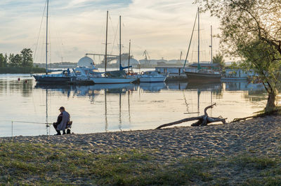 Sailboats moored at harbor against sky