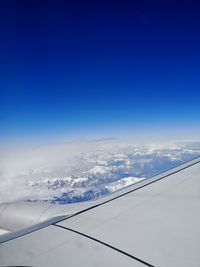 Aerial view of snowcapped mountain against blue sky