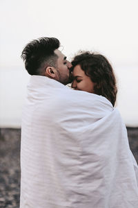 Young couple kissing against clear sky