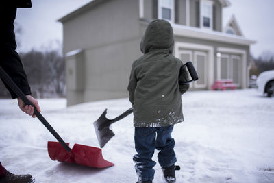 Cropped image of father with son removing snow at yard