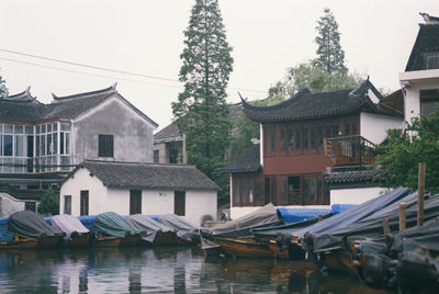 Houses by lake and buildings against sky