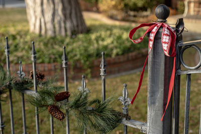 Red ribbon green garland decorations hanging along vintage wrought iron fence