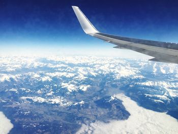 Aerial view of snowcapped mountains against blue sky