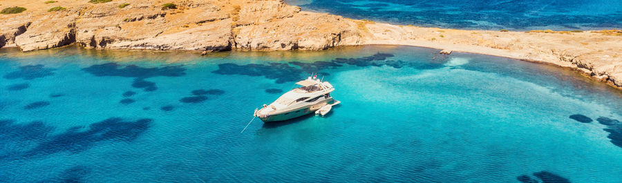 View from above, stunning aerial view of a bay with boat, luxury yacht sailing on a turquoise water