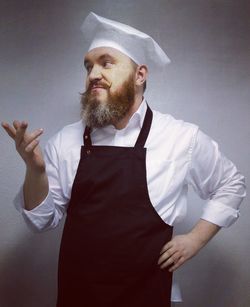 Thoughtful chef gesturing against gray background