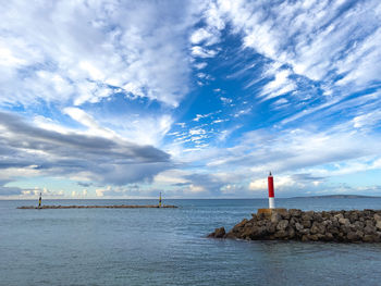 Lighthouse by sea against sky