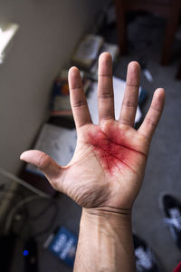 Low section of man showing blood on palm at home