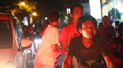 Group of people standing on illuminated city at night