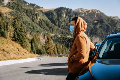 Man with mask standing on road by mountain