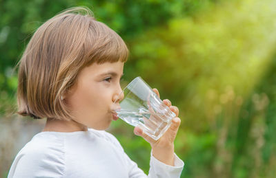 Close-up of young woman drinking water in park