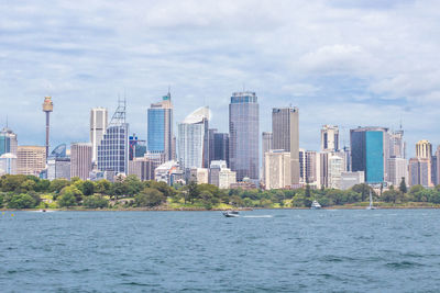 Sea by modern buildings against sky in city