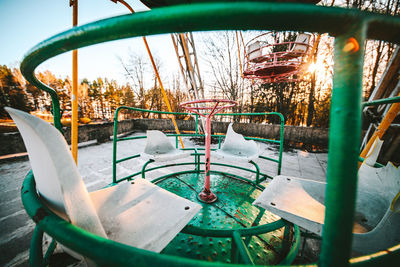 Empty chairs and tables in park against sky during winter