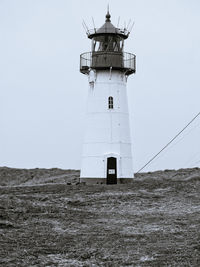 Low angle view of lighthouse on field against sky