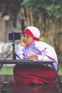 Boy looking away while sitting outdoors