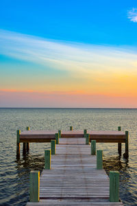 Pier over sea against sky during sunset