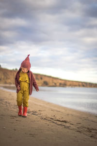 Girl standing on beach against sky