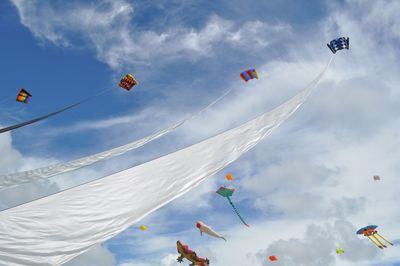 Low angle view of colorful kites flying against cloudy sky