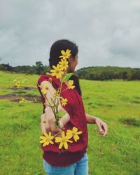 Woman holding flowers on field