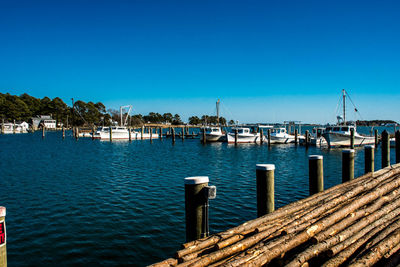 Pier on sea against clear blue sky