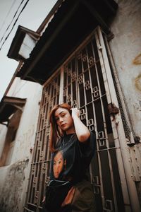 Portrait of young woman standing against building
