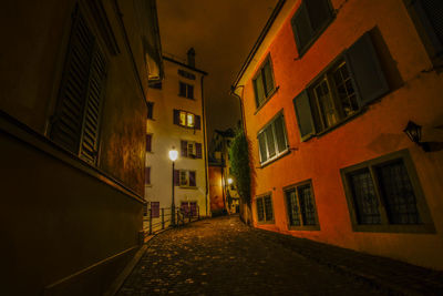 Empty alley amidst buildings in city at night