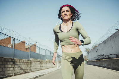 Woman running on road against blue sky