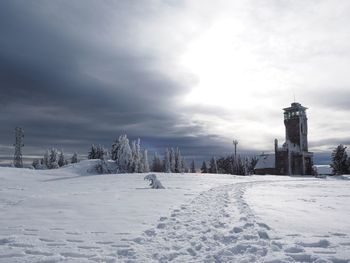 Scenic view of snow covered field against cloudy sky