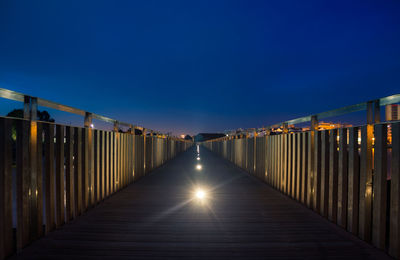 Illuminated footbridge against clear blue sky