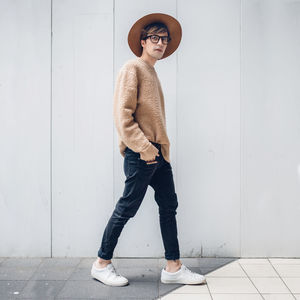Full length portrait of a young man standing on wall