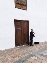 Full length of man playing violin on sidewalk